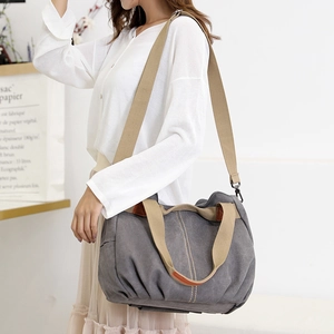 Retro large canvas shoulder bag in grey with khaki handles shown on model in minimalist room