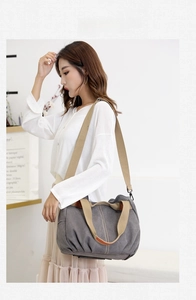 Side view of large gray canvas crossbody bag worn by model in a minimalist home setting
