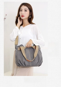 Detail of gray canvas tote with brown handles and adjustable strap in lifestyle shot