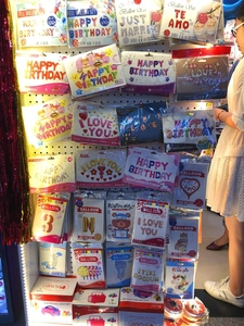 Assorted birthday party balloon kits and electric air pumps displayed in a retail store setting
