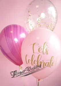 Detail of pink celebratory balloon with gold lettering, marble pattern, and gold confetti fill