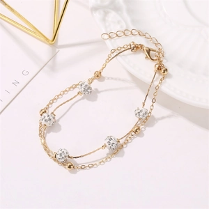 Detailed view of a gold-plated double-layer anklet with zircon-studded shambhala beads