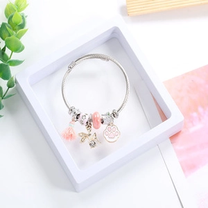 Detail of beaded charm bracelet with pink tassel, cat paw pendant and butterfly on tray