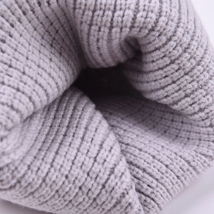 Close-up of light gray knitted beanie showing thick wheat stitch texture and soft lining