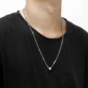 Close-up of a silver cube pendant necklace worn by a model in a casual black t-shirt