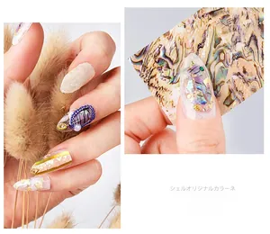 Macro detail of 3D iridescent shell nail art charms with gold foil and pearls stickers