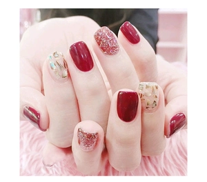 Macro detail of wine red and iridescent shell flake nail stickers on manicured hands