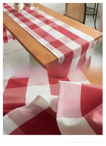 Detail van rood-witte geruite tafelloper met stoftextuur en dubbele stikselafwerking
