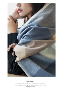 Close-up of thick blue and beige plaid scarf with soft tassels and cozy texture