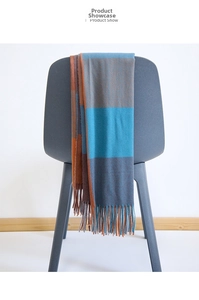 Detail view of thickened blue and brown plaid scarf with long fringe hanging on chair