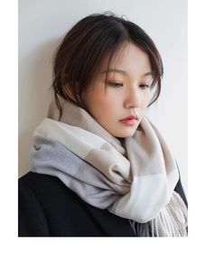 Close-up of a soft plaid scarf in beige and grey wool blend worn by a model