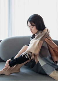 Close-up of thick plaid scarf with tassels in beige and blue on a model in soft light