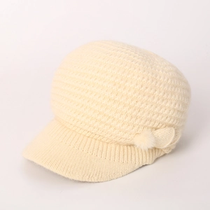Detail der Strickstruktur und weicher Bommel an der cremeweißen Damen Wintermütze
