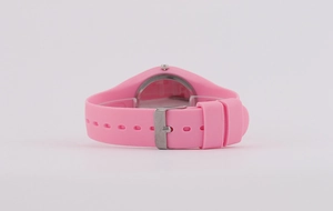 Detail of pink silicone watch strap with metal buckle and adjustment holes on white backdrop
