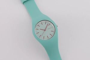 Detail of mint green silicone quartz watch featuring white dial and red hands