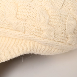 Detalle de punto trenzado crema y borde acanalado en la gorra de punto de invierno