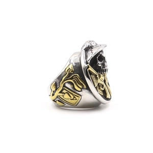 Detail of silver skull ring with gold ace of spades and floral embossed pattern