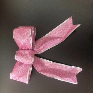 Macro shot of 15cm pink glitter Christmas bow with fine silver stitched edge on black background