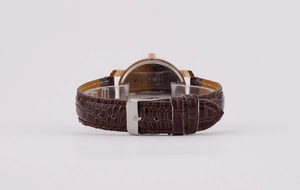 Detail of brown faux crocodile leather watch strap with silver buckle and rose gold case