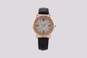 Macro detail of rose gold watch case with crystal bezel and black leather strap