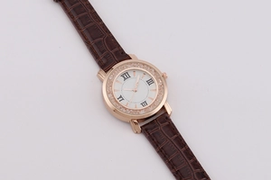 Detail of rose gold watch with crystal bezel and brown leather strap on white background