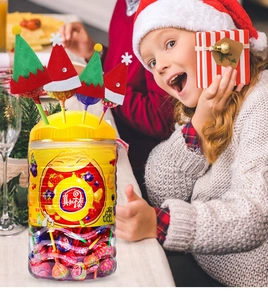 Close-up of lollipops decorated with festive mini red Santa hats and elf felt covers
