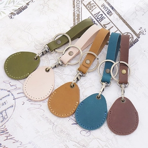 Bovenaanzicht van vijf druppelvormige lederen sleutelhangers in groen, beige, blauw en bruin