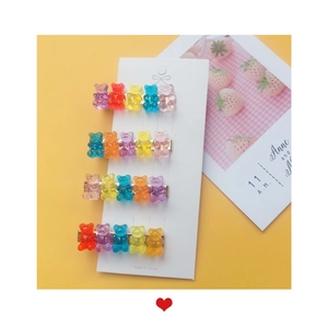 Set of four colorful acrylic gummy bear hair clips with gold metal bases on a display card