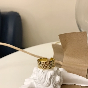 Detail of a golden floral hollow ring with resin flower set on a stone base