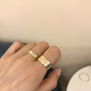 Close-up of golden floral and quilted pattern rings worn on fingers with warm lighting