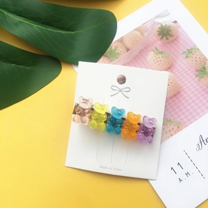 Close-up of five colorful candy-colored acrylic bear hair clips on a white display card