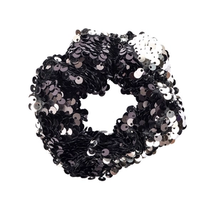 Close-up of two-tone black and silver reversible sequin hair scrunchie with shiny texture