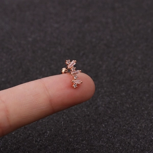 Macro detail of rose gold cartilage barbell earring with cubic zirconia on a finger