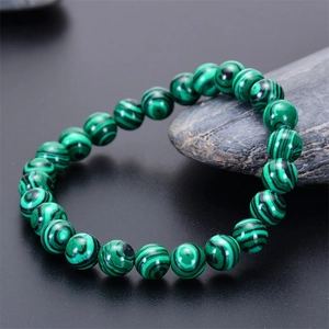 Macro detail of natural green malachite beaded bracelet with black stripes on a stone
