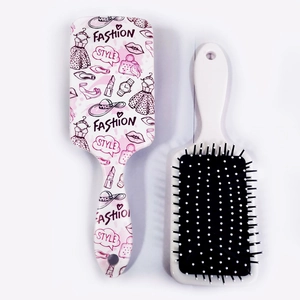 Detail view showing dual sides of floral plastic hairbrush with soft white bristles