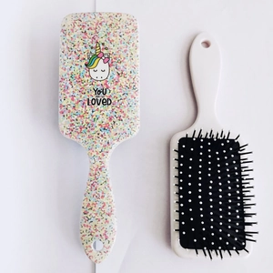 Close-up of cute cartoon unicorn hairbrush with You Are So Loved text and white air cushion