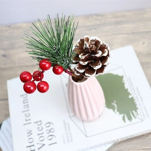 Christmas tree decoration with red berries, pine needles and pink ceramic vase on wood table
