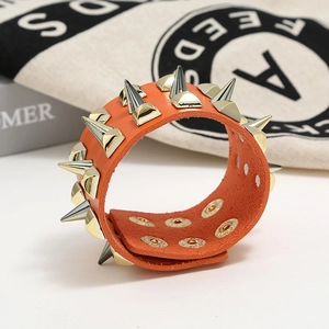 Detail of orange leather punk bracelet with gold spikes and adjustable snap buttons