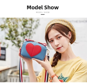 Detail of blue pebble leather mini bag with red heart patch and colorful woven strap