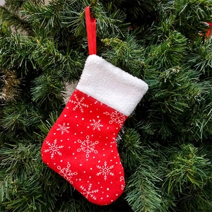Red Christmas stocking with snowflake pattern and white fur trim on a festive tree