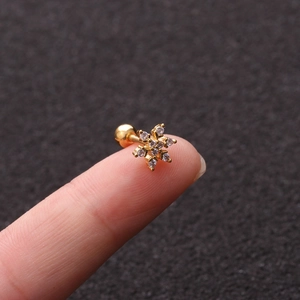 Macro view of a gold star-shaped screw back earring with zircon stones on a fingertip
