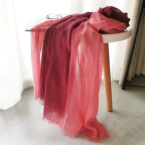 Detail of red and coral pink gradient linen scarf with fringe edges on a white table