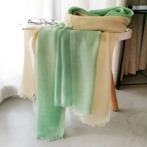 Detailed texture of green and beige gradient linen scarf with natural tassel edges