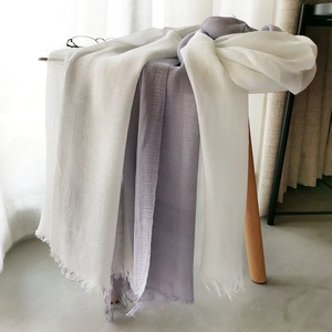 Detail of white and purple cotton linen scarves with tassels on a wooden stand