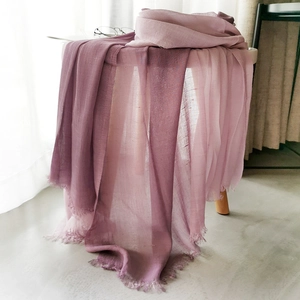 Detail of purple gradient cotton linen scarf with elegant fringe texture on a table