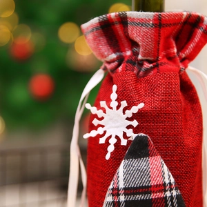 Close-up of red burlap Christmas wine gift bag with snowflake patch and plaid trim