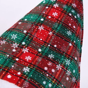 Close-up of thick red and green plaid Christmas fabric with golden thread and snowflakes