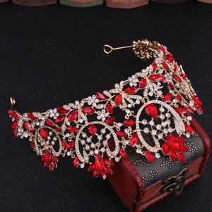 Close-up of golden Baroque crown with red leaf gems and rhinestones on vintage wood box