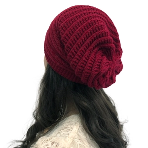 Detail showing the burgundy knitted beanie texture and slouchy design on a model