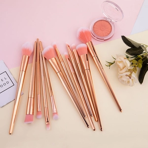 Detail of 12pcs rose gold makeup brushes with pink gradient bristles on aesthetic background